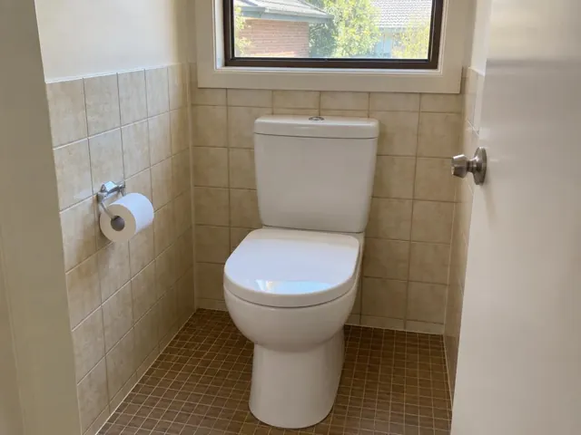 Clean white toilet in a tiled bathroom with a small window in Kellyville